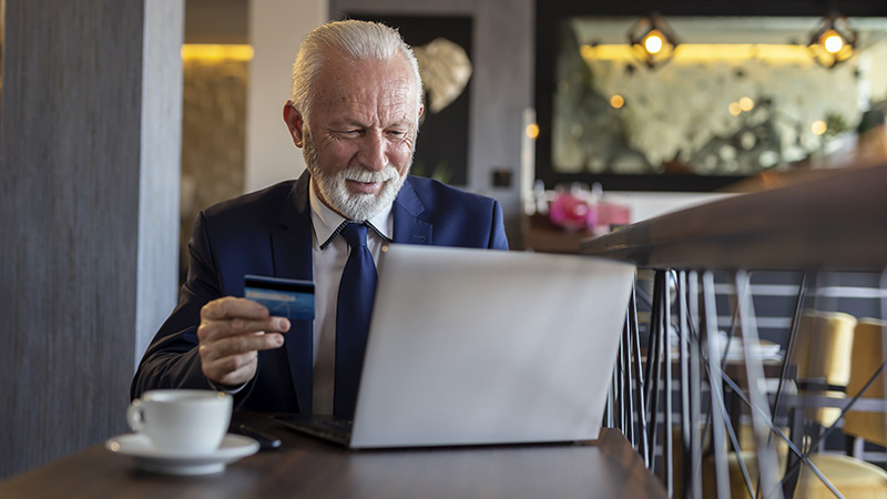 man on laptop paying with credit card