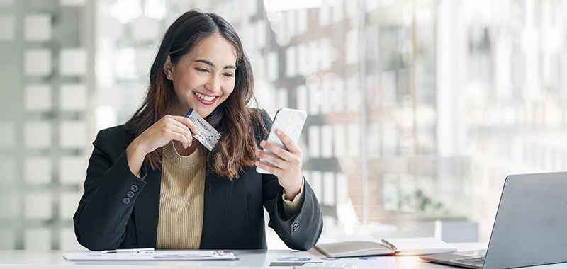 woman holding credit card and looking a phone